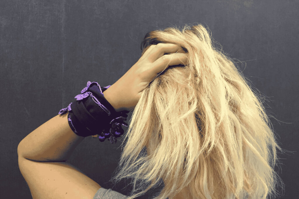 Dry, frizzy blonde hair affected by hard water in the UAE – woman holding hair from the back